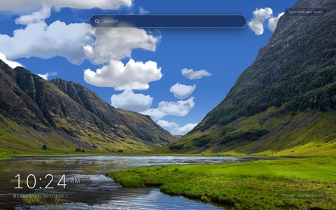 Highland Loch New Tab theme: a photograph of a loch between steep green and grey hills under a blue sky with white clouds, with rippled shallow water in the left foreground and a bright green grass bank on the right